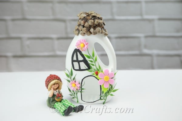 Fairy house with a fairy sitting next to it