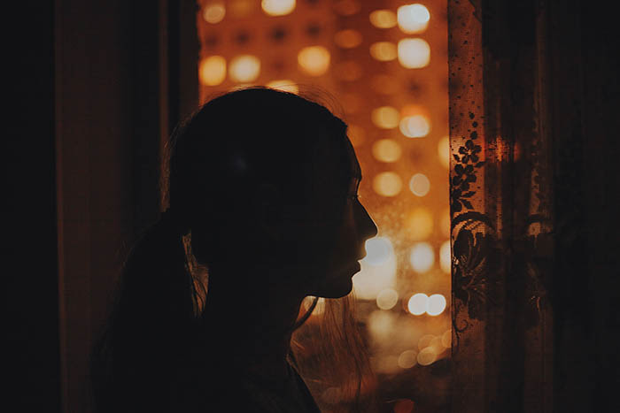 a silhouette self-portrait of a long haired girl in front of a windowsill